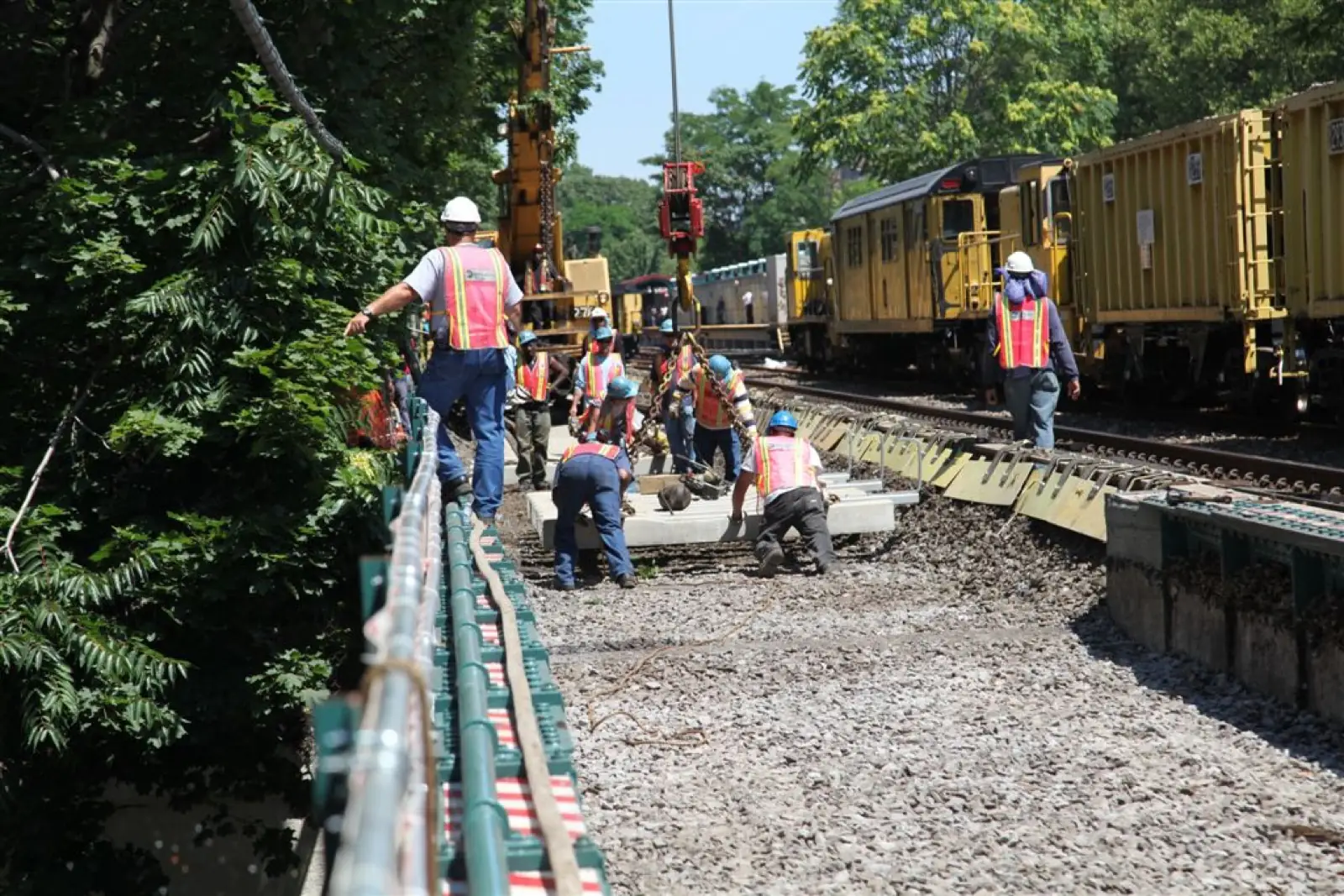 Track crew setting a concrete panel beside a work train