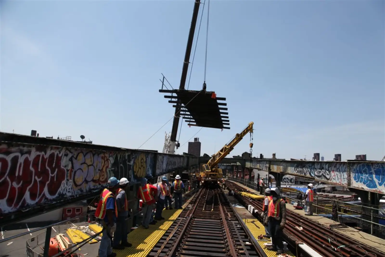 Track crew gathered beside the rail watching a panel lift