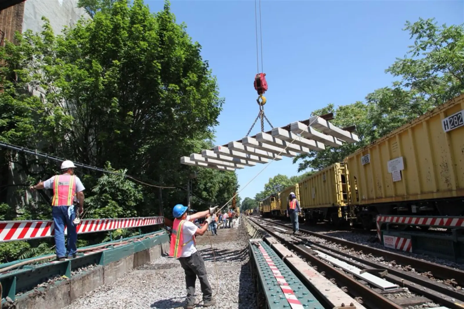 Track crew placing a timber-tie panel beside the rail
